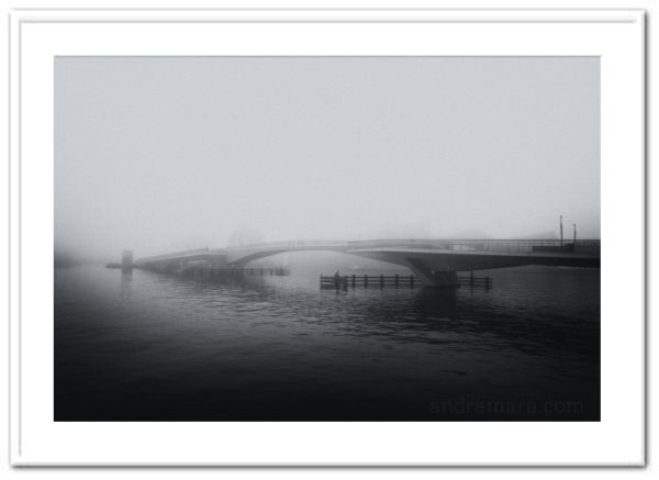 Fog lays thick over a bridge. Black and white film