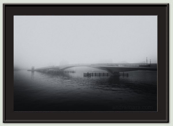 Fog lays thick over a bridge. Black and white film